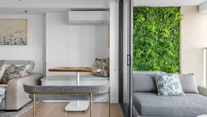 Een moderne woonkamer met een grijze bank, een klein tafeltje en een groene verticale gevelwand.