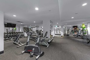 A modern gym with cardio machines, free weights, and a TV screen. - Sweet! 1bed, 1bath, 1car, Views ~ CBD (Brisbane)
