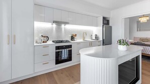 Een moderne keuken met witte kasten, een centraal eiland en een inbouwoven.