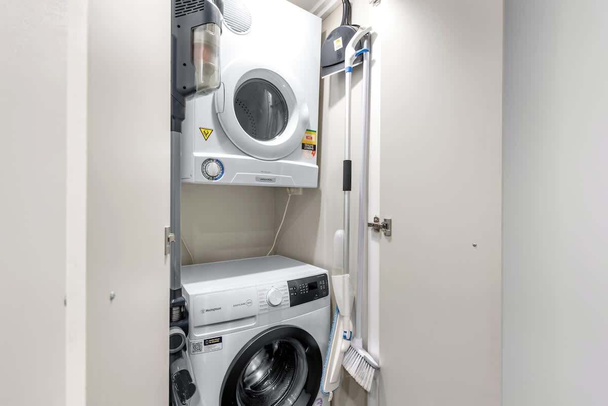 Une petite buanderie équipée d’un lave-linge à chargement frontal et d’un sèche-linge à chargement par le haut.