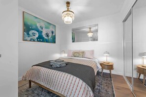 A bedroom with a bed, a chandelier, a painting, a mirror, and a bedside table. - Sweet! 1bed, 1bath, 1car, Views ~ CBD (Brisbane)