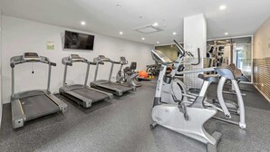 Et fitnesscenter med løbebånd, crosstrainer og styrkemaskiner.