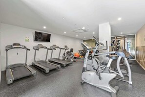 Ein Fitnessstudio mit Laufbändern, Crosstrainern und Kraftgeräten.