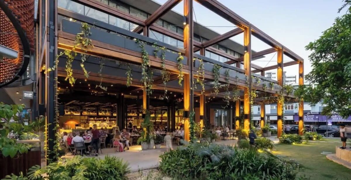 Un espace de restauration en plein air, avec des tables et des chaises, entouré de verdure et de plantes.