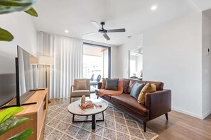 Ein modernes Wohnzimmer mit einer Couch, einem Couchtisch, einem Fernseher und einem Deckenventilator.