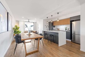 Eine moderne Küche mit einem Holzesstisch, Barhocker und einem Edelstahlkühlschrank.