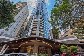 A modern hotel with a curved entrance, large pillars, and a prominent number '222' sign. - Skyrise Style! 1bed/1bath/1car/views! ~ CBD (Brisbane)