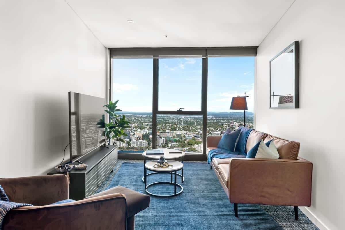 A modern living room with a large window, a sofa, a coffee table, and a TV.