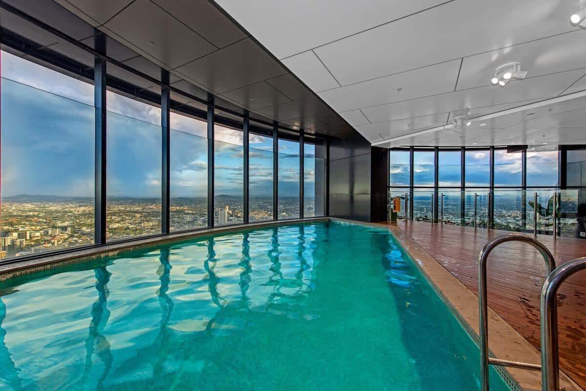 A modern indoor swimming pool with large windows offering a city view.