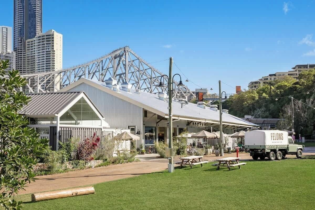 A building with a metal framework, a truck labeled 'FELONS,' and a picnic area.