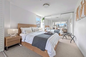 A modern bedroom with a large bed, bedside tables, a mirror, and a city view. - Wow! ~ Skyline City, Water + Story Bridge Views (Brisbane)