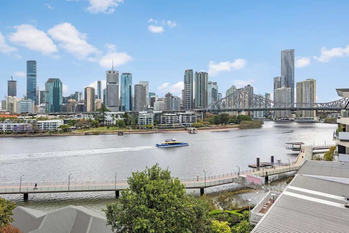 A city skyline with modern buildings, a river, and a bridge.