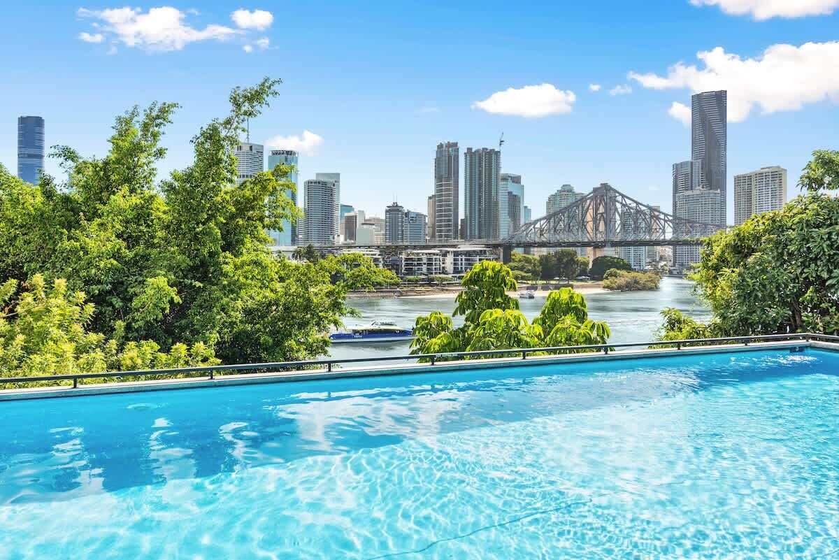 A swimming pool with a city skyline and a bridge in the background.