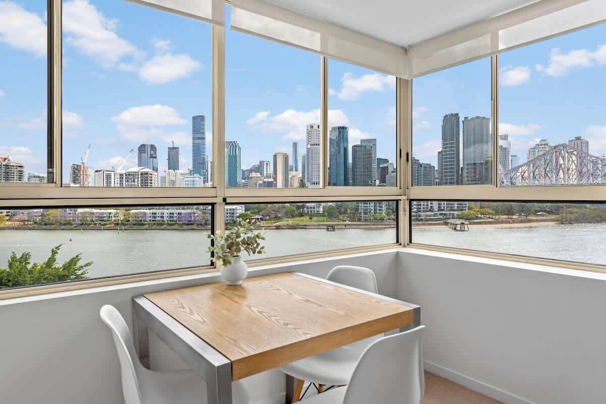 A room with a large window overlooking a city skyline and a river.