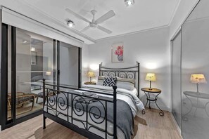 A bedroom with a bed, two bedside tables, a ceiling fan, and a sliding glass door leading to a balcony. - South Bank Central! ~ 2bed, 2bath, 1car, 2balcony (Brisbane)