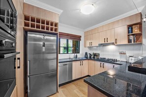 A modern kitchen with stainless steel appliances, wooden cabinets, and a granite countertop. - Point Peninsula - 2bed-2bath-car-pool - Teneriffe (Brisbane)