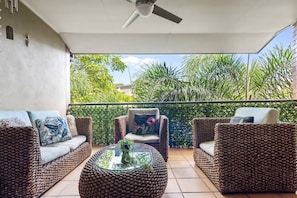 A balcony with wicker furniture, a glass coffee table, and a view of greenery. - Point Peninsula - 2bed-2bath-car-pool - Teneriffe (Brisbane)
