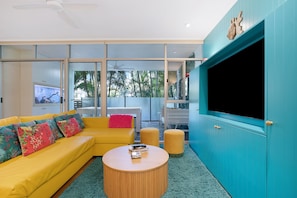 A modern living room with a yellow sofa, a round coffee table, and a large teal cabinet. - The Fishbowl! 1bed/1bath/1car/pool (Brisbane)