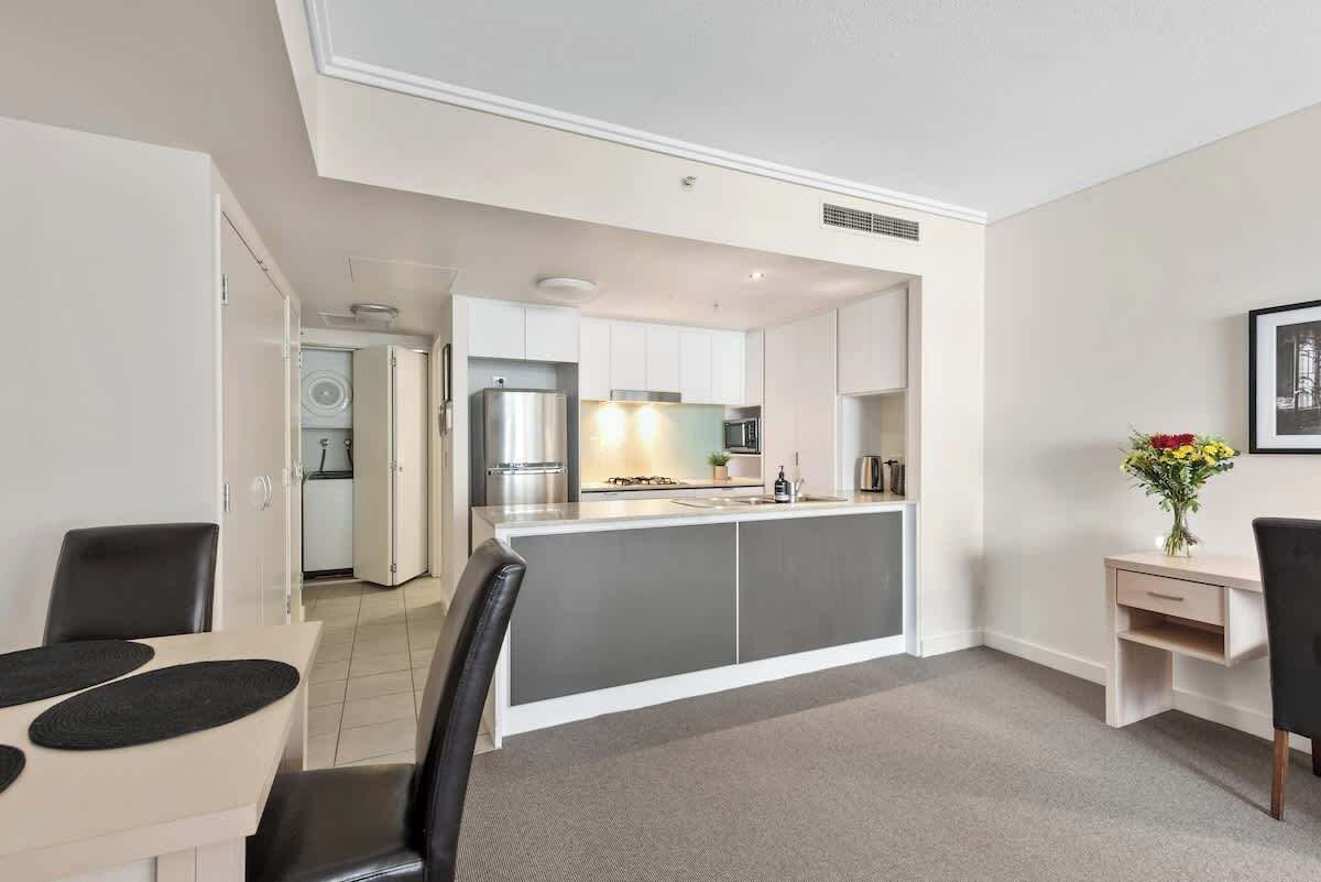 A modern kitchen with white cabinets, a stainless steel refrigerator, and a central island.