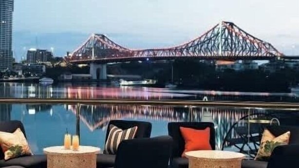 A poolside seating area with chairs and small tables, a view of a bridge, and a cityscape in the background. - Heart of the CBD ~ 1bed/1bath/balcony/free Parking (Brisbane)