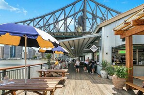 A waterfront restaurant with outdoor seating, a view of a bridge, and a sign for 'FELONS'. - Modern on Mary! 1 Bed,1 Bath,1 Car, Views! (Brisbane)
