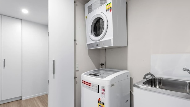 Een wasserette met een wasmachine, droger en wasbak.