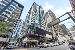 A modern urban street with high-rise buildings, a commercial area with shops, and a busy road with vehicles. - South Bank Sensational! ~ 2bed/2bath/1car/pool! (Brisbane)