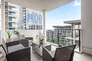 A balcony with wicker furniture, a glass table, and a potted plant. - South Bank Sensational! ~ 2bed/2bath/1car/pool! (Brisbane)