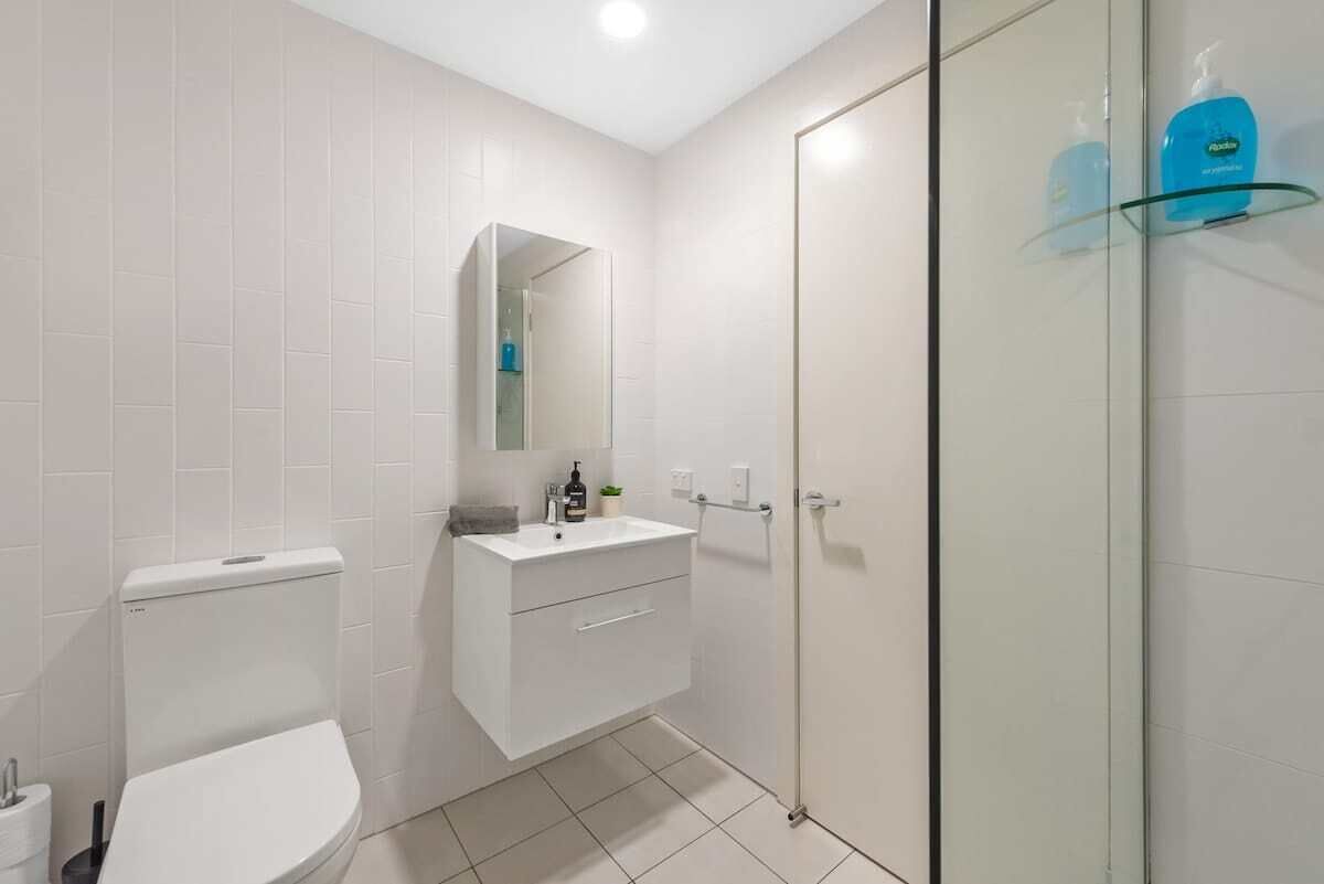 A bathroom with a toilet, a sink, a mirror, and a glass shower enclosure.
