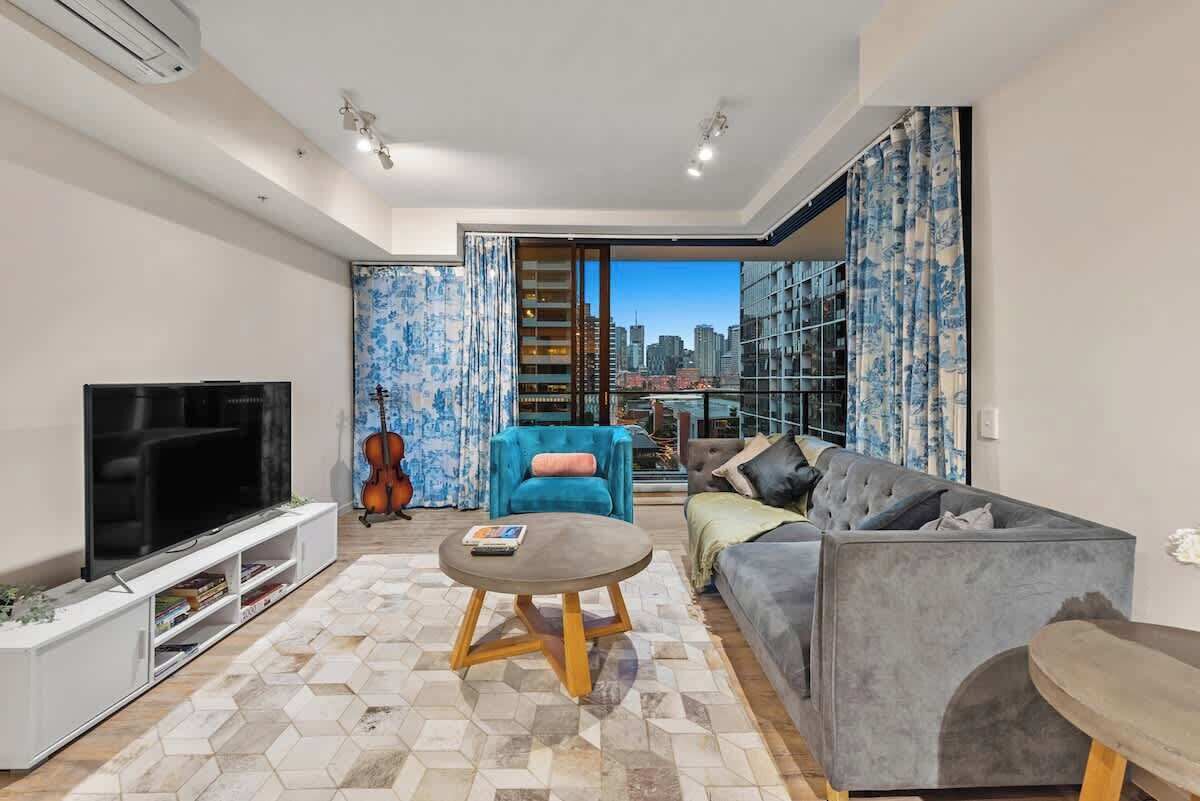 A modern living room with a flat-screen TV, a round coffee table, a sofa, and a blue armchair.