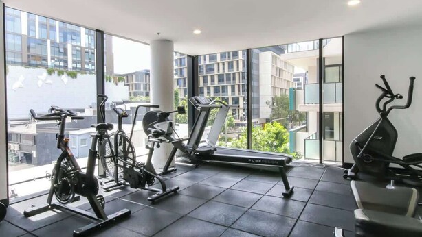 A gym with exercise equipment, large windows, and a view of buildings. - South Bank Stunner! ~ 3 Bed/2 Bath/1car/views (Brisbane)