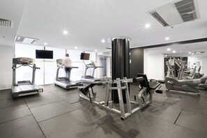 A gym with treadmills, a weight machine, and a TV screen. - Urban Retreat 1bed-1bath-study-balcony-1car (Brisbane)