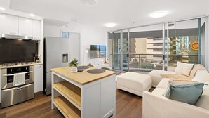 A modern kitchen with stainless steel appliances, a wooden island, and a glass sliding door leading to a balcony. - Urban Retreat 1bed-1bath-study-balcony-1car (Brisbane)