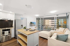 A modern kitchen with stainless steel appliances, a wooden island, and a glass sliding door leading to a balcony. - Urban Retreat 1bed-1bath-study-balcony-1car (Brisbane)