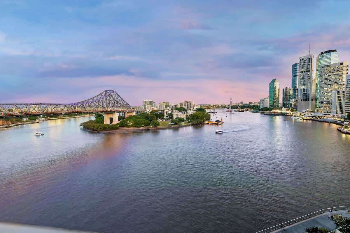 A river with a bridge, city skyline, and boats.