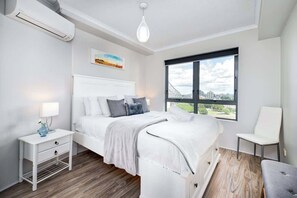 A modern bedroom with a bed, bedside table, lamp, and a window with a city view. - Spectacular! 2bed, 1bath, 1car, Views ~ CBD (Brisbane)