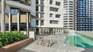 A rooftop pool area with lounge chairs, a pool, and a building with multiple floors in the background. - Top of the Town! 2bed/2bath/1car/balcony/views~cbd (Brisbane)