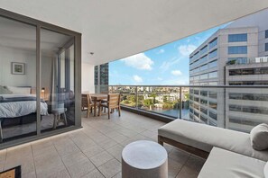 Ein Balkon mit einem Bett, einem Esstisch und einer Couch.