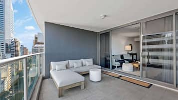 A modern balcony with a sofa, a small table, and a view of the cityscape.