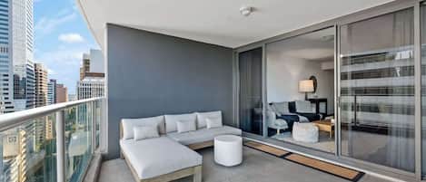 A modern balcony with a sofa, a small table, and a view of the cityscape.