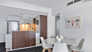 A modern kitchen with white cabinets, a wooden island, and a round dining table with four chairs. - Top of the Town! 2bed/2bath/1car/balcony/views~cbd (Brisbane)