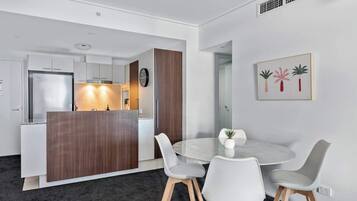 A modern kitchen with white cabinets, a wooden island, and a round dining table with four chairs.