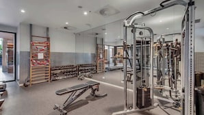 Ein Fitnessraum mit Krafttrainingsgeräten, Bänken und Kurzhanteln.