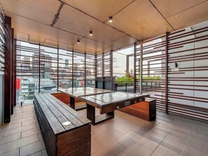 A modern indoor space with a pool table, wooden benches, and large windows offering city views. - Resort-style Living! ~ 1bed/1bath/1car (Brisbane)