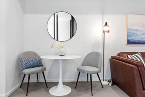 A room with a round mirror, two chairs, a white table, a floor lamp, a brown sofa, and a framed picture on the wall. - Resort-style Living! ~ 1bed/1bath/1car (Brisbane)