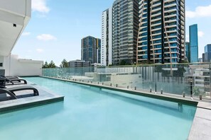 A rooftop pool with a glass railing, surrounded by high-rise buildings. - Resort-style Living! ~ 1bed/1bath/1car (Brisbane)