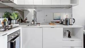 Eine moderne Küche mit weißen Schränken, einem Backofen, einer Spüle und einer Kaffeemaschine.