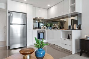 A modern kitchen with stainless steel appliances, white cabinetry, and a central island. - Resort-style Living! ~ 1bed/1bath/1car (Brisbane)