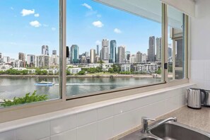 Eine Küche mit einem großen Fenster, das auf eine Stadtlandschaft und einen Fluss blickt.