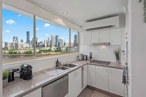 Eine moderne Küche mit Stadtblick, weißen Schränken und einem großen Fenster.